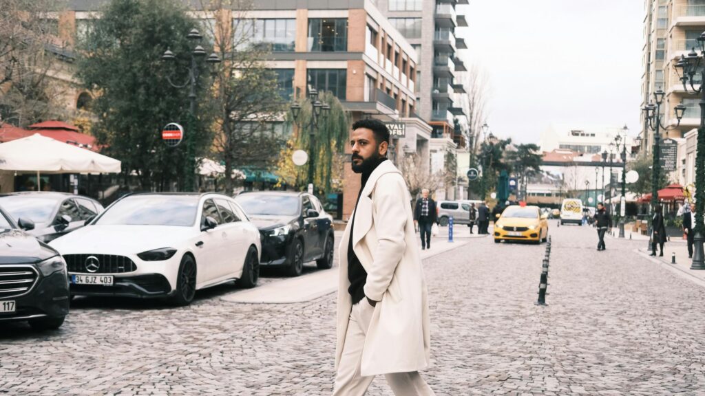 Stylish Man in Cream Coat Walking Through City Street 4K Desktop Wallpaper