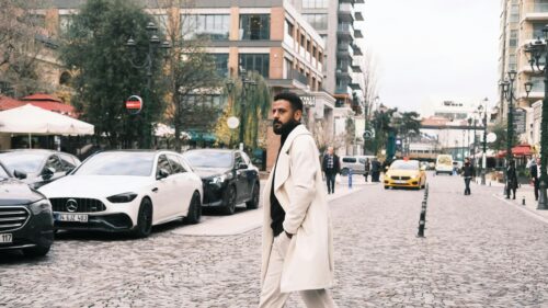 Stylish Man in Cream Coat Walking Through City Street 4K Desktop Wallpaper