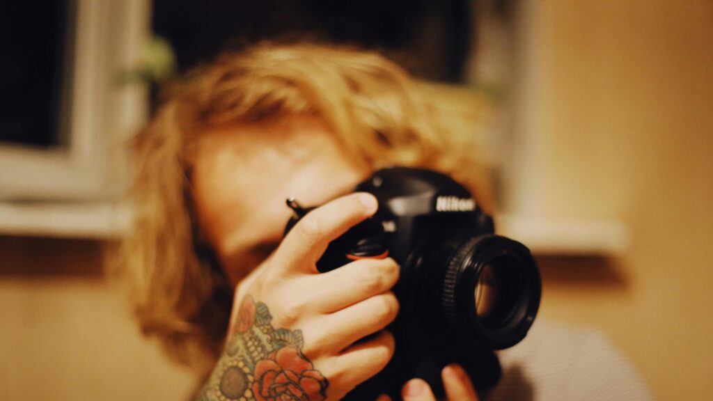 Creative Photographer with Floral Tattoo Holding DSLR Camera PC Wallpaper