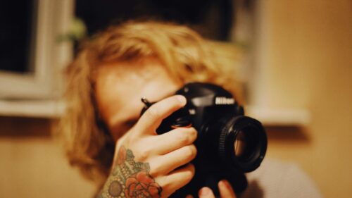 Creative Photographer with Floral Tattoo Holding DSLR Camera PC Wallpaper