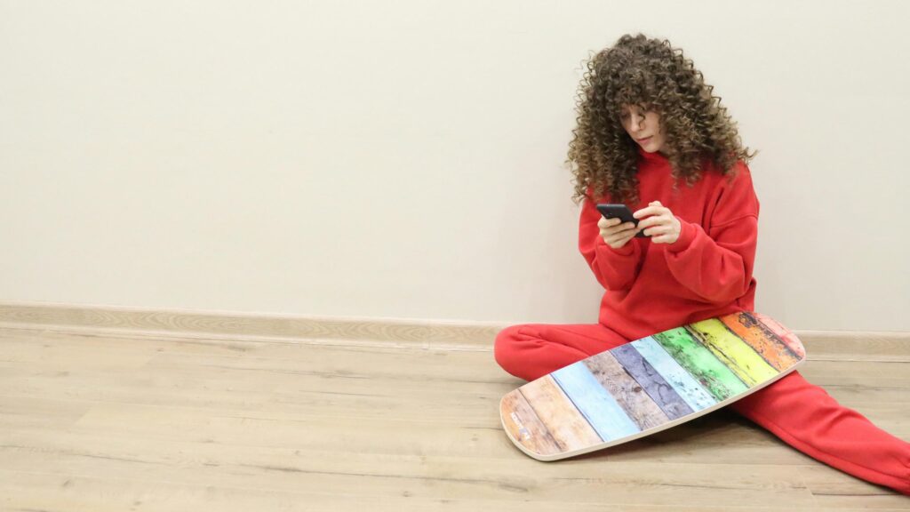 Curly Girl in Red Hoodie With Rainbow Balance Board Desktop Wallpaper