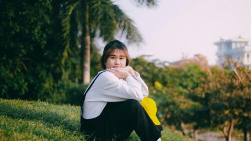 Young Woman Resting on Grassy Hillside Outdoors 4K Wallpaper
