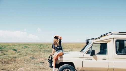 Woman Sitting on Safari Land Cruiser in Open Savannah Desktop Wallpaper