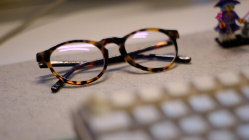 Tortoiseshell Glasses and Miniature Desk Figurine 4K Desktop Wallpaper