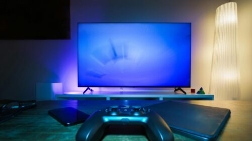 Cozy Gaming Setup with Glowing Blue Screen and Controller 4K Wallpaper