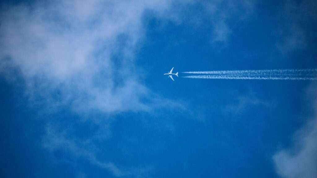 Airplane Soaring Through Blue Skies With Contrails PC Wallpaper