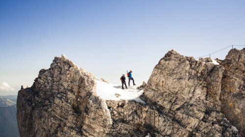 Hikers Standing on Snowy Alpine Mountain Peak 4K Wallpaper