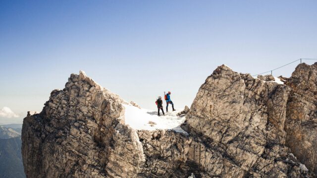 Hikers Standing on Snowy Alpine Mountain Peak 4K Wallpaper
