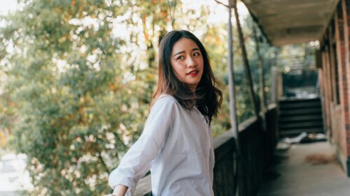 Stunning Asian Woman Looking Away on a Sunny Balcony 4K Wallpaper