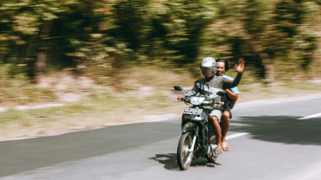Two Men Riding a Motorcycle Through a Scenic Forest Road Desktop Wallpaper