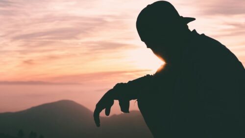 Silhouette of a Person Sitting at Sunset Over Mountains 4K Wallpaper