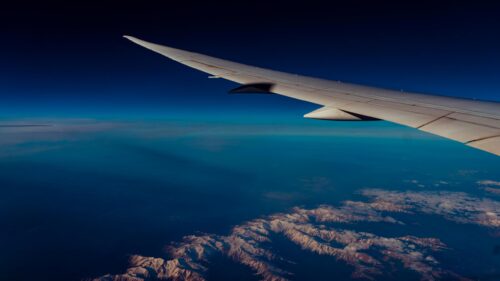 Aerial View of Snowy Mountain Peaks from Airplane Wing 4K Wallpaper