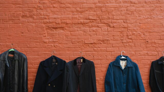 Minimalist Vintage Coats on Red Brick Wall 4K Desktop Wallpaper