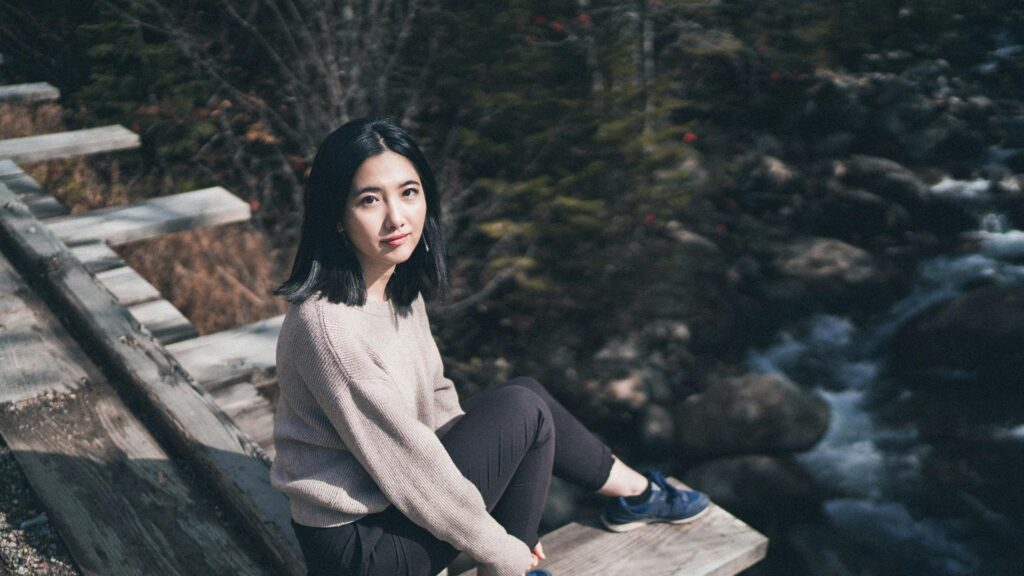 Asian Girl Sitting on Wooden Trailside Bench Desktop Wallpaper