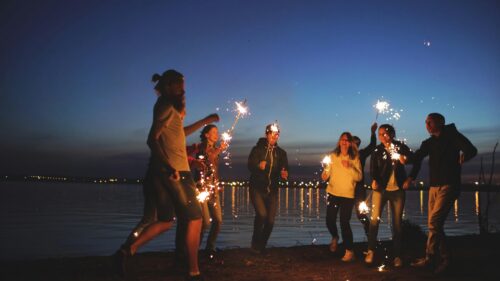 Friends Holding Sparklers at Sunset Beach Party 4K Desktop Wallpaper