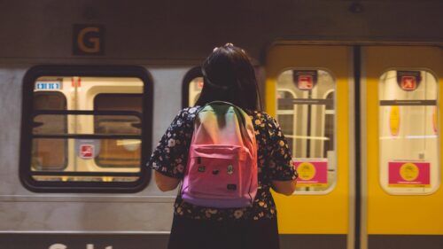 Girl Standing on Subway Platform with Rainbow Backpack Desktop Wallpaper