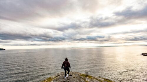Solitary Hiker Standing on Coastal Cliff Edge 4K Wallpaper