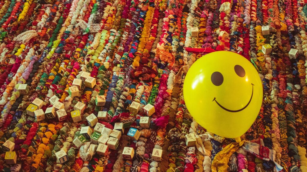 Happy Yellow Smiley Face Balloon on Colorful Rag Rug Desktop Wallpaper