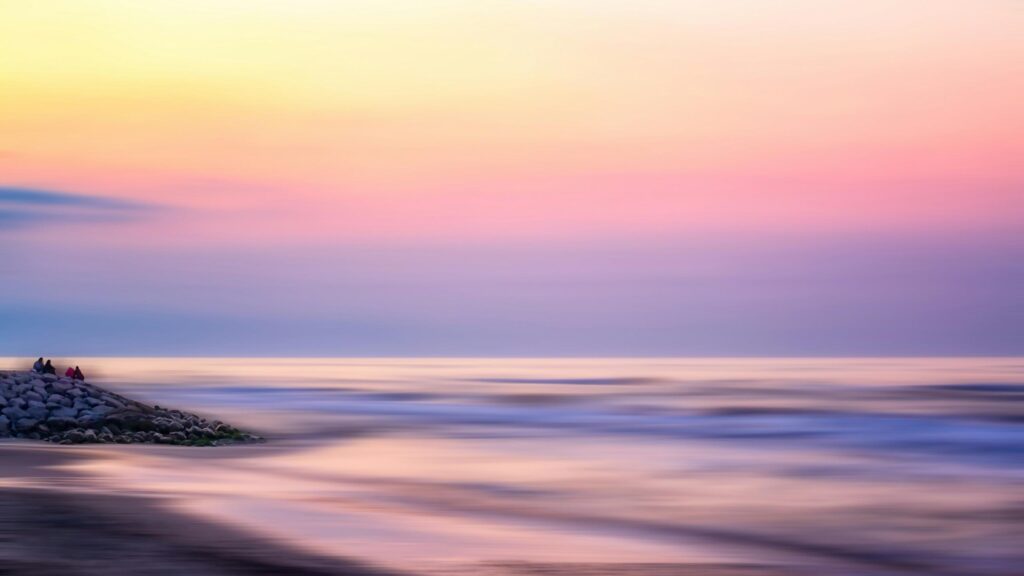 Dreamy Pastel Seascape with People on Rocks Desktop Wallpaper