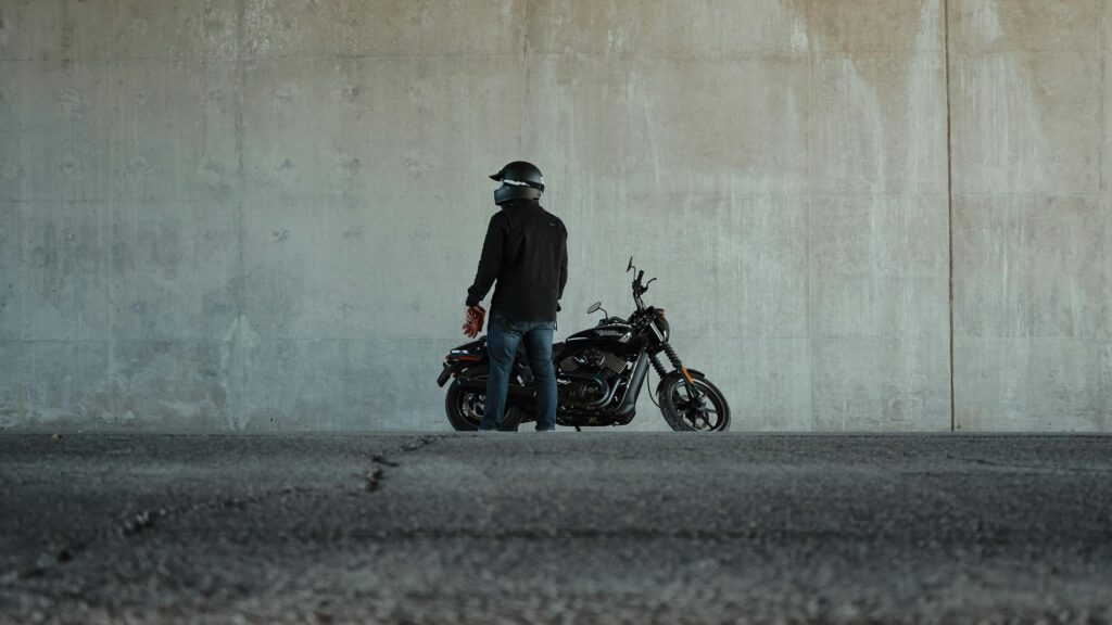 Biker with Black Harley Davidson Motorcycle Against Concrete Wall 4K Wallpaper