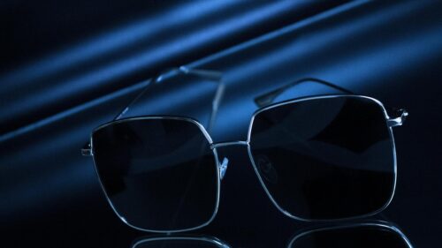 Elegant Minimalist Sunglasses on Reflective Dark Blue Silk Desktop Wallpaper