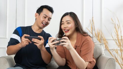 Young Couple Excitedly Playing Mobile Games Desktop Wallpaper