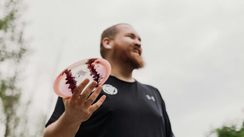 Professional Disc Golfer Holding Custom Disc Mania Frisbee 4K Wallpaper