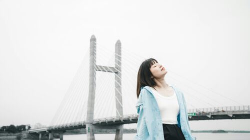 Serene Young Woman Breathing Fresh Air Near a Modern Suspension Bridge Desktop Wallpaper