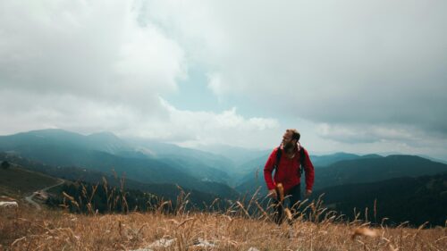 Hiker in Red Jacket Standing on Mountain Ridge Desktop Wallpaper