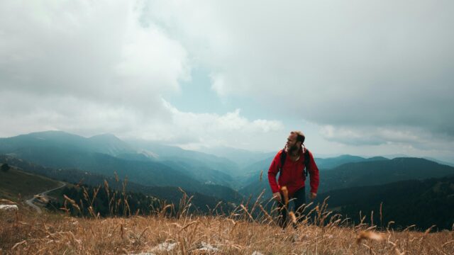 Hiker in Red Jacket Standing on Mountain Ridge Desktop Wallpaper
