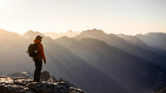 Hiker Standing on Mountain Peak at Sunset 4K Wallpaper