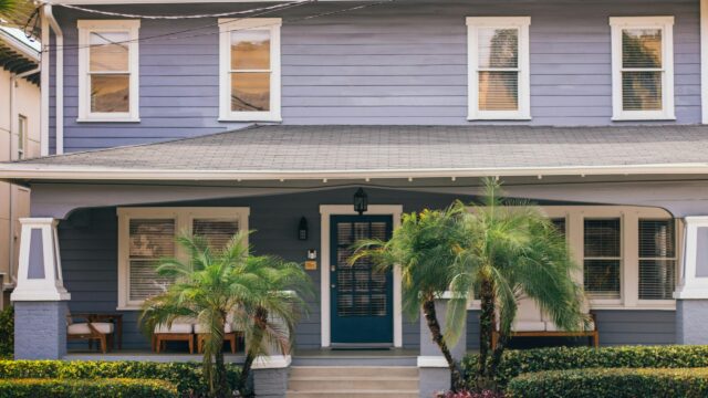 Charming Blue Suburban House Porch with Tropical Plants Desktop Wallpaper