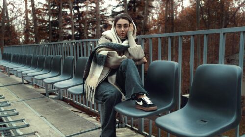 Woman Sitting on Stadium Seats in Autumn Park 4K Desktop Wallpaper