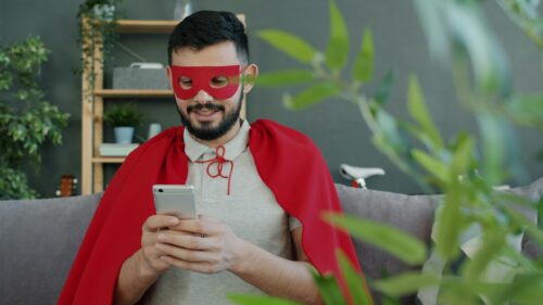 Funny Superhero Man with Red Cape and Mask Using Smartphone 4K Wallpaper