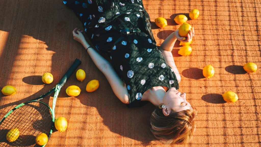 Woman Lying on Clay Tennis Court with Lemons Desktop Wallpaper