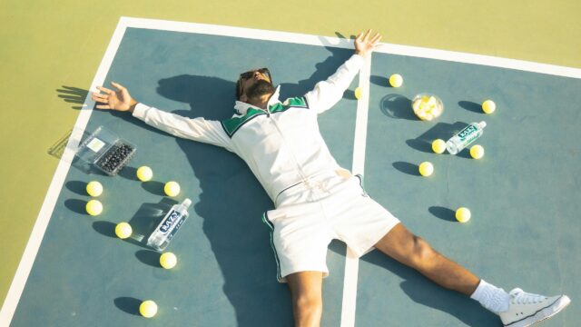 Man Relaxing on Tennis Court with Fruit and Water 4K Wallpaper