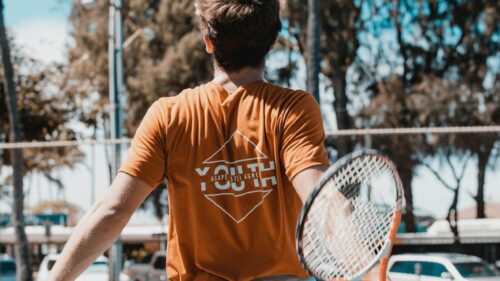 Young Tennis Player in Orange T-Shirt Back View Desktop Wallpaper
