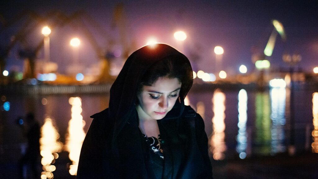 Thoughtful Woman in Hooded Coat at Night City Harbor 4K Wallpaper