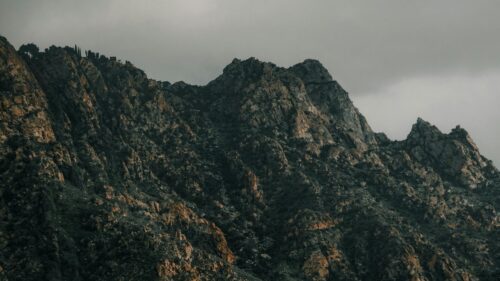 Rugged Mountain Peaks Under Dramatic Stormy Skies Desktop Wallpaper