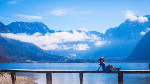 Woman Sitting on Wooden Pier by Mountain Lake Scenic 4K Wallpaper