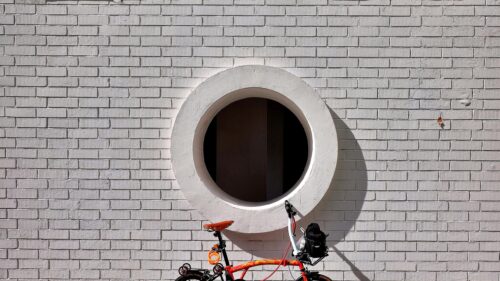 Minimalist Orange Folding Bicycle Against White Brick Wall 4K Wallpaper