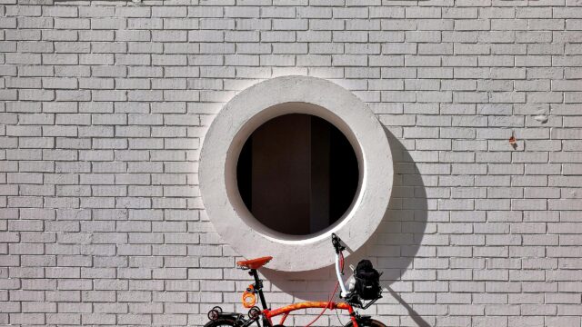 Minimalist Orange Folding Bicycle Against White Brick Wall 4K Wallpaper