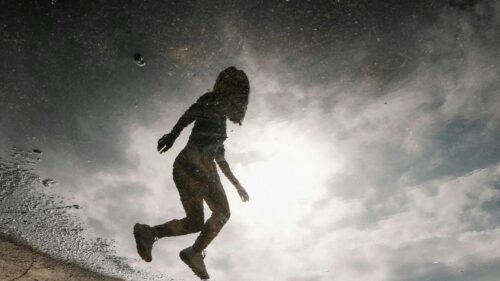 Silhouette of a Person Jumping in a Puddle Reflection Desktop Wallpaper