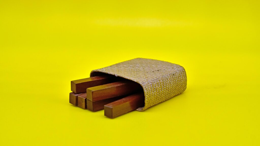 Minimalist Wooden Sticks in Woven Case on Bright Yellow 4K Wallpaper