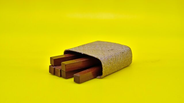 Minimalist Wooden Sticks in Woven Case on Bright Yellow 4K Wallpaper