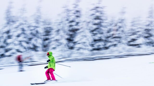 Skier in Neon Jacket Gliding Through Snowy Mountain Forest 4K Wallpaper
