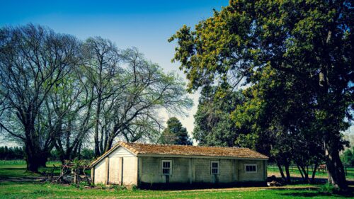 Rustic Farmhouse Under Lush Green Trees Desktop Wallpaper