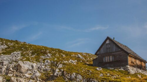 Rustic Wooden Alpine Hut on a Mountain Slope 4K Desktop Wallpaper