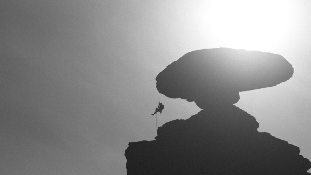 Silhouette Rock Climber Rappelling Under Mushroom Rock Desktop Wallpaper