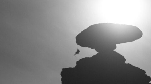 Silhouette Rock Climber Rappelling Under Mushroom Rock Desktop Wallpaper